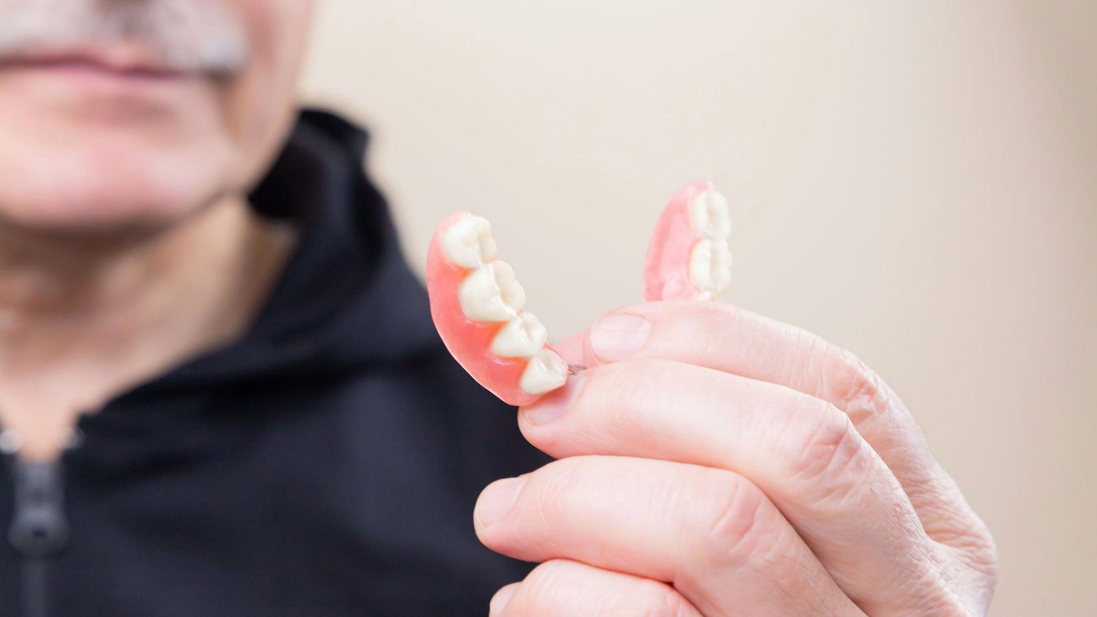 older-man-holding-dentures-in-his-hand